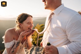The bride laughs after a champagne sip mishap while wiping her mouth with the groom’s tie at The Chimneys, North Carolina